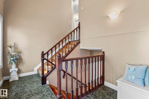 The property features a staircase with dark wood banisters and balusters, complemented by a tiled floor - 9610 167 Street Sw, Edmonton, AB - Indoor Photo Showing Other Room