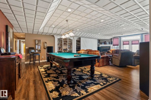This expansive recreation room features wood-style flooring, a billiards table with an overhead light fixture, and a large decorative area rug - 9610 167 Street Sw, Edmonton, AB - Indoor Photo Showing Other Room