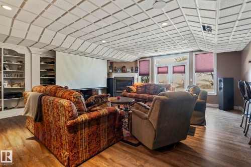 This inviting living space features wood-style flooring, a fireplace, and a large projection screen - 9610 167 Street Sw, Edmonton, AB - Indoor With Fireplace