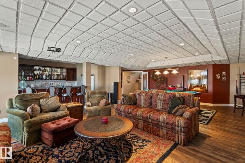 This spacious room features hardwood flooring, a recessed ceiling with integrated lighting, and a built-in bar area with seating - 9610 167 Street Sw, Edmonton, AB - Indoor Photo Showing Living Room