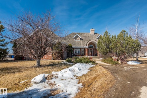 The property features a brick exterior with a prominent arched entry and a shingle roof - 9610 167 Street Sw, Edmonton, AB - Outdoor