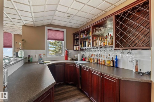 This area features rich wood cabinetry with a wine rack and glass storage, complemented by a tiled backsplash - 9610 167 Street Sw, Edmonton, AB - Indoor Photo Showing Kitchen