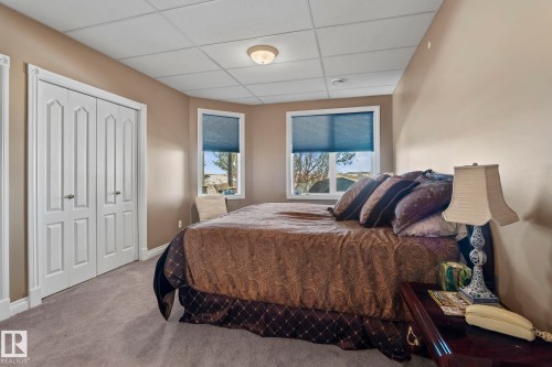 This bedroom features a neutral color palette, plush carpet flooring, and white bi-fold closet doors - 9610 167 Street Sw, Edmonton, AB - Indoor Photo Showing Bedroom