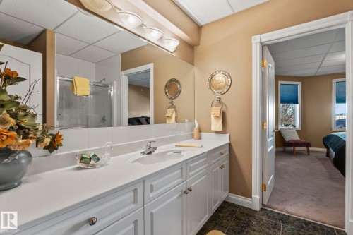 This bathroom features a spacious vanity with a white countertop, extensive mirror, and overhead lighting - 9610 167 Street Sw, Edmonton, AB - Indoor Photo Showing Bathroom