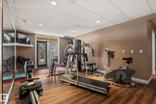 This well-appointed room features recessed lighting, durable flooring, and a glass-paneled door providing external access - 9610 167 Street Sw, Edmonton, AB - Indoor Photo Showing Gym Room