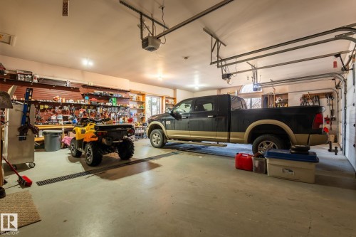 This spacious garage features a concrete floor with drainage, overhead garage door rails, and built-in shelving providing extensive storage - 9610 167 Street Sw, Edmonton, AB - Indoor Photo Showing Garage