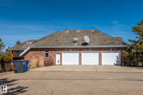 The property features a brick exterior, a multi-car garage with three white doors, and a shingled roof - 9610 167 Street Sw, Edmonton, AB - Outdoor