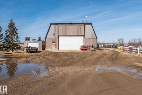 The property features a large metal-sided building with a prominent overhead door and an entry door - 9610 167 Street Sw, Edmonton, AB - Outdoor