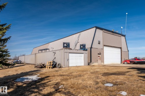 The property features a large industrial-style building with a metal exterior, equipped with a wide garage door and an additional smaller garage door - 9610 167 Street Sw, Edmonton, AB - Outdoor