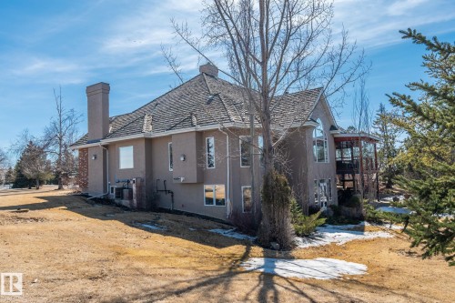 The property features a stucco exterior, a prominent chimney, and a multi-level deck - 9610 167 Street Sw, Edmonton, AB - Outdoor