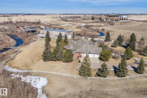 The property features a spacious yard with mature trees and a distinctive white fence, bordering a natural waterway - 9610 167 Street Sw, Edmonton, AB - Outdoor With View