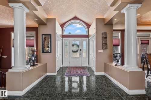 The entryway features a vaulted ceiling, a white paneled door with an arched transom window, and dark tiled flooring - 9610 167 Street Sw, Edmonton, AB - Indoor Photo Showing Other Room