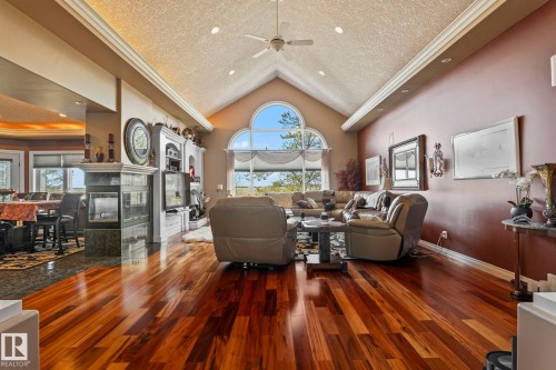 The living room features high vaulted ceilings, expansive hardwood flooring, and a large arched window - 9610 167 Street Sw, Edmonton, AB - Indoor