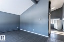 The property features vaulted ceilings, dark plank flooring, and a kitchen area with a refrigerator and window - 15204 94 Street, Edmonton, AB  - Indoor Photo Showing Other Room 
