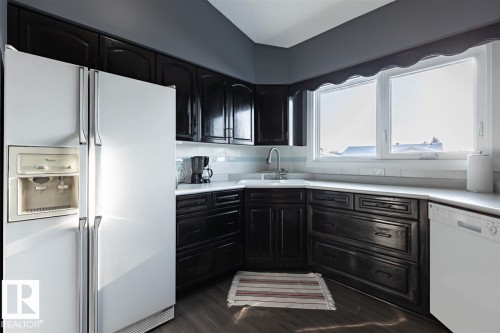 Kitchen featuring dark cabinetry, white countertops, and a white tile backsplash - 15204 94 Street, Edmonton, AB - Indoor Photo Showing Kitchen