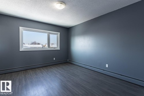 This room features dark grey walls, a white window frame, and wood-look flooring - 15204 94 Street, Edmonton, AB - Indoor Photo Showing Other Room