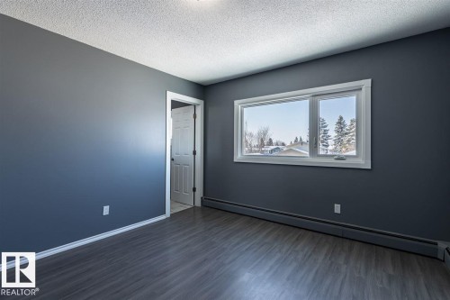 This room features dark gray walls, light gray flooring, and a window with white trim - 15204 94 Street, Edmonton, AB - Indoor Photo Showing Other Room