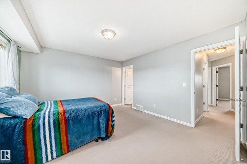 Spacious room featuring light-colored carpet, light grey walls, and a window with white curtains - 105 13825 155 Avenue, Edmonton, AB - Indoor Photo Showing Bedroom