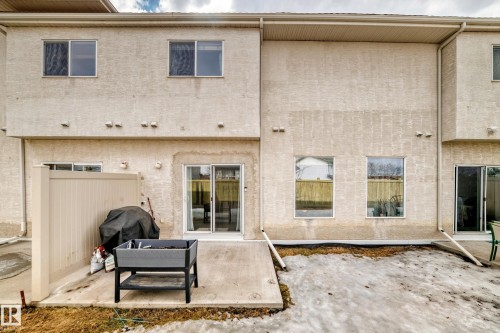 The property features a stucco exterior, a ground-level patio, and sliding glass doors - 105 13825 155 Avenue, Edmonton, AB - Outdoor With Exterior