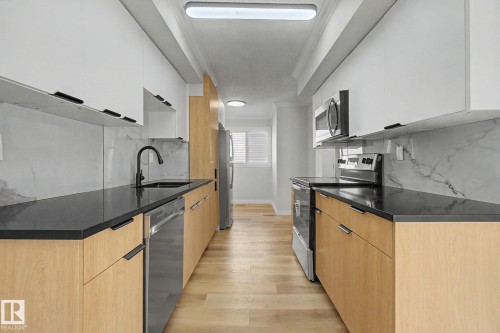 The kitchen features light wood lower cabinetry, white upper cabinetry, and dark countertops - 186 Centennial Crest, Edmonton, AB - Indoor Photo Showing Kitchen With Upgraded Kitchen