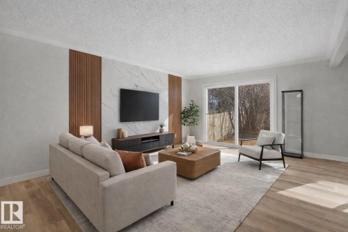 Living area featuring light wood flooring, a textured accent wall with wood paneling and a marble-patterned section, and sliding glass doors that provide natural light - 186 Centennial Crest, Edmonton, AB - Indoor Photo Showing Living Room