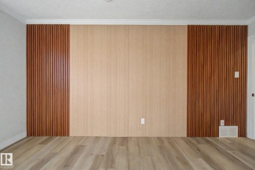 The property features light-toned flooring, a wall with two vertical wood panel sections, and a central lighter wood panel - 186 Centennial Crest, Edmonton, AB - Indoor Photo Showing Other Room