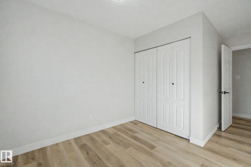 This room features light-colored walls, light wood-style flooring, and a closet with bifold doors - 186 Centennial Crest, Edmonton, AB - Indoor Photo Showing Other Room