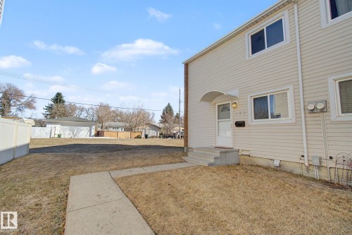 The property features a light-colored exterior, an inviting front entry with a protective awning, and a well-maintained lawn area - 186 Centennial Crest, Edmonton, AB - Outdoor