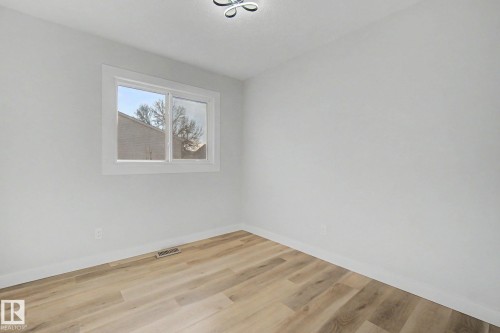 This room features light-colored walls, a window with white trim, and light wood-style flooring - 186 Centennial Crest, Edmonton, AB - Indoor Photo Showing Other Room