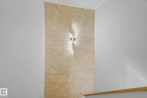 Accent wall featuring light-colored stone tiling and a modern curved sconce - 186 Centennial Crest, Edmonton, AB - Indoor