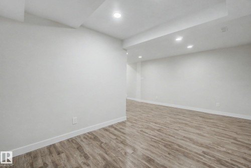 This expansive room features light-colored walls, recessed lighting, and wood-style flooring - 186 Centennial Crest, Edmonton, AB - Indoor Photo Showing Other Room