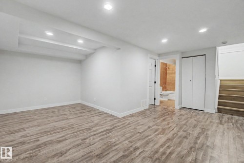 Spacious open area featuring recessed lighting, light-toned wood-style flooring, a double-door closet, and access to a bathroom with a tiled shower - 186 Centennial Crest, Edmonton, AB - Indoor Photo Showing Other Room
