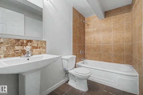 Bathroom featuring a pedestal sink, a toilet, a bathtub with shower, and tiled walls and floor - 186 Centennial Crest, Edmonton, AB - Indoor Photo Showing Bathroom