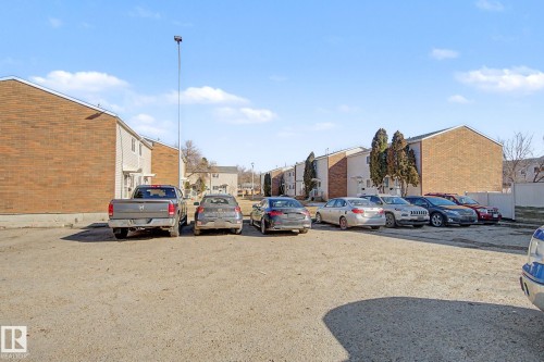 The property features a parking area with a gravel surface, bordered by buildings with brick and siding exteriors - 186 Centennial Crest, Edmonton, AB - Outdoor