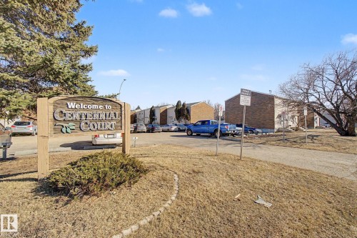Welcome sign for Centennial Court at the entrance of the property, featuring a surrounding lawn area and mature trees - 186 Centennial Crest, Edmonton, AB - Outdoor
