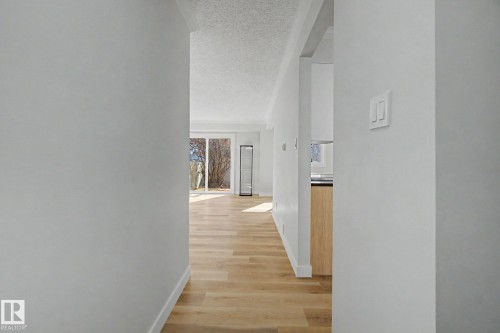 Hallway featuring light wood flooring, white walls, and a view into a living area with sliding glass doors - 186 Centennial Crest, Edmonton, AB - Indoor Photo Showing Other Room