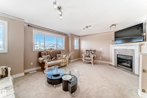 The living room features large windows, carpeted flooring, and a fireplace with a mantel - 11415 167A Avenue, Edmonton, AB - Indoor Photo Showing Living Room With Fireplace