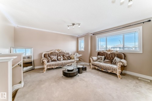 This expansive living space features large windows, crown molding, and neutral-toned walls, creating a bright and inviting atmosphere - 11415 167A Avenue, Edmonton, AB - Indoor Photo Showing Living Room
