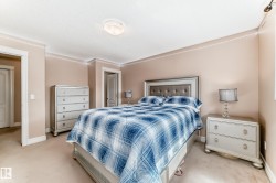 This inviting bedroom features neutral-toned walls, carpeted flooring, and crown molding - 