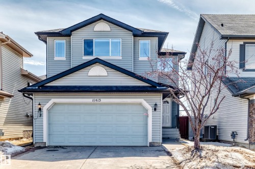 This property features light blue siding, a dark roof, and a double garage with a light blue door - 11415 167A Avenue, Edmonton, AB - Outdoor