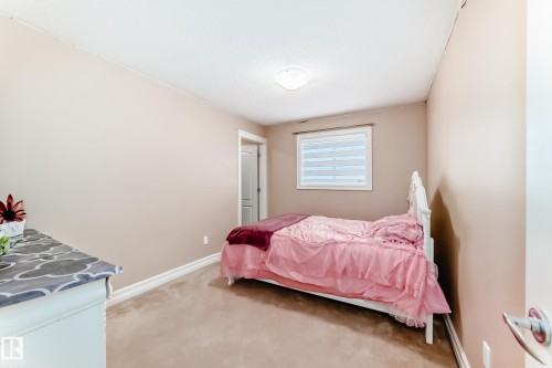 This room features a neutral wall color, carpeted flooring, and a window with blinds - 11415 167A Avenue, Edmonton, AB - Indoor Photo Showing Bedroom