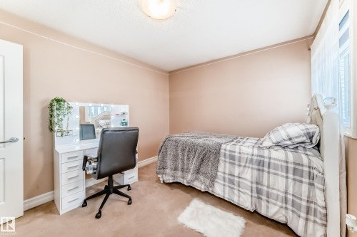 This room features soft-toned walls, carpeting, and a window with sheer white curtains - 11415 167A Avenue, Edmonton, AB - Indoor Photo Showing Bedroom