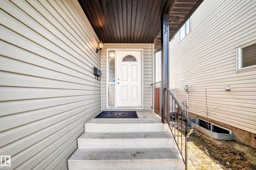 The property features a white paneled front door with an arched window, complemented by an exterior light fixture - 11415 167A Avenue, Edmonton, AB - Outdoor With Exterior