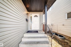 The property features a white paneled front door with an arched window, complemented by an exterior light fixture - 