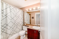 The bathroom features a vanity with a white sink, a mirror, and overhead lighting - 
