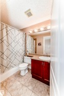 The bathroom features a vanity with a dark wood cabinet, a white sink, and a light-colored countertop, along with a toilet and a bathtub with a shower curtain - 