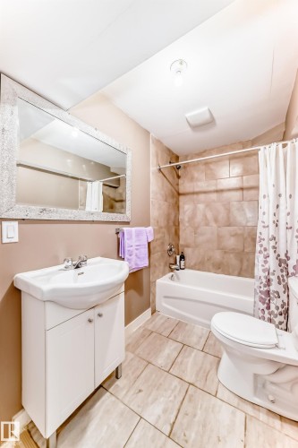 Bathroom featuring a vanity with an integrated sink, a bathtub with a shower, and tiled flooring - 11415 167A Avenue, Edmonton, AB - Indoor Photo Showing Bathroom