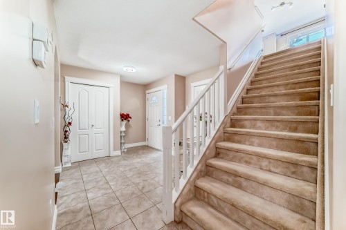 The property features an entryway with tiled flooring and a carpeted staircase with a white banister, leading to a window - 11415 167A Avenue, Edmonton, AB - Indoor Photo Showing Other Room