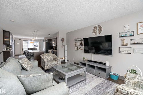The open concept living area features light gray walls, dark wood flooring, and recessed lighting - 7776 Eifert Crescent Nw, Edmonton, AB - Indoor Photo Showing Living Room