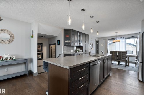 The property features an open-concept kitchen with a central island, stainless steel appliances, and dark wood cabinetry - 7776 Eifert Crescent Nw, Edmonton, AB - Indoor Photo Showing Kitchen With Double Sink With Upgraded Kitchen
